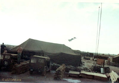 Operations Tent with Operations Sgt Pete
Dave Jones Photo

A/227 Operations Tent with Sgt Pete on sandbags watching A/227 fly by.
Camp Evans 1968
