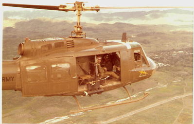 Overlapping Blades
Terry Moore Photo

787 pictured. The crew member in the foreground is Warren and in the background seated by console is Joe Paranal the crew chief, July 1971, Formation flight from Camp Holloway over the Red Ball near Kontum. Photo taken from 749.

