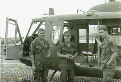 Lai Khe Flight Line 
Wayne Trucke Photo

Wayne Trucke on left. The man on the right is Mike Scovall, according to SP4 Bert Hibberd, AKA "Mr. Flib". Bert says Scovall is the guy who designed the "Chickenman" patch.
 WO1 Tim Hope is in the middle - identified by Allen Russell

