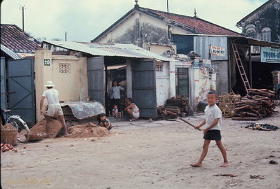 Phan Thiet back streets
Bob Kelly Photo

Construction sand, laundry (upper right) and boy playing stick ball. Homemade ladder center right. Man in Vietnamese squat in center.
